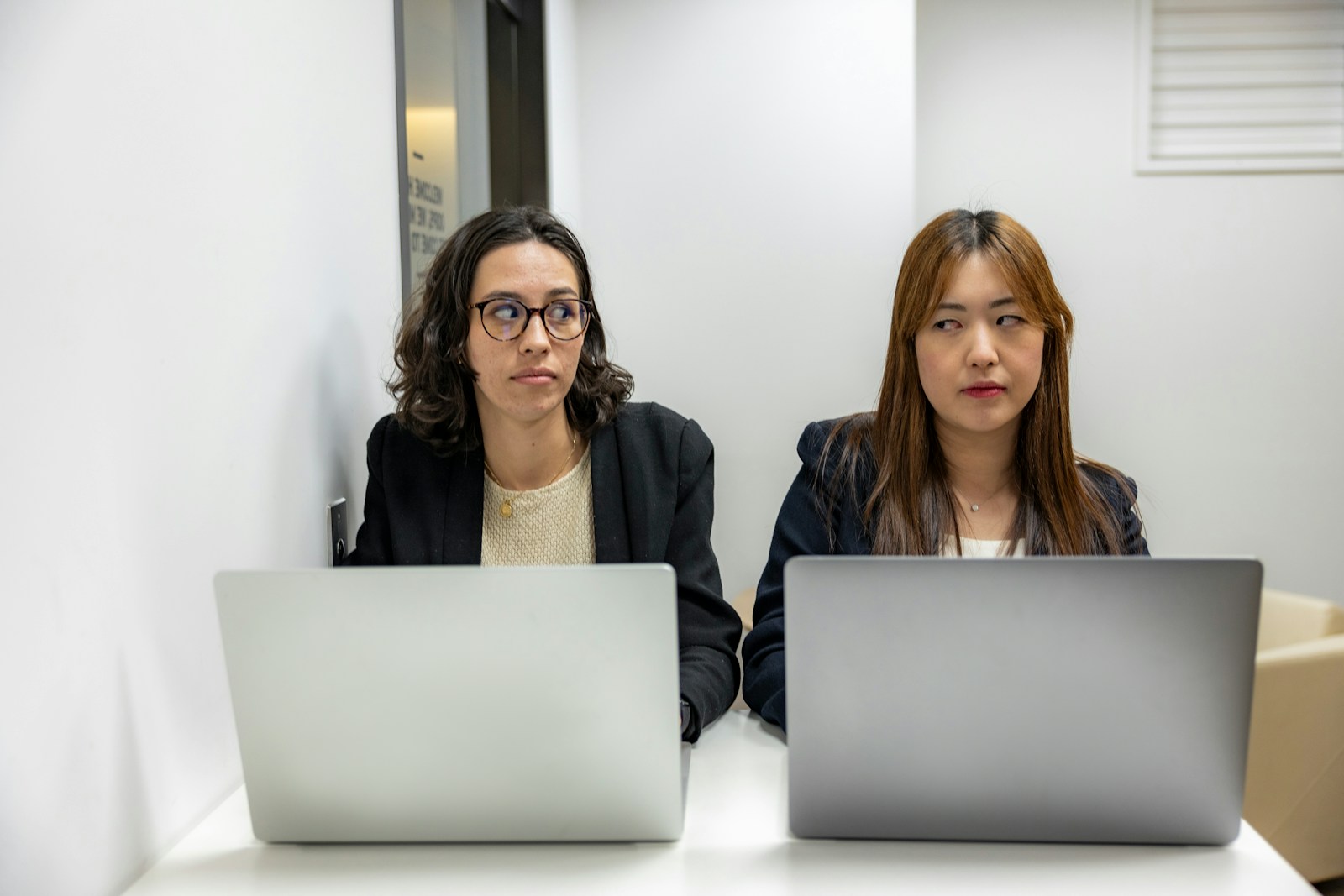 two women sitting at a table with laptops